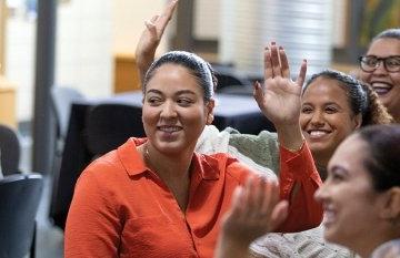 Students sitting together, smiling, raising their hands